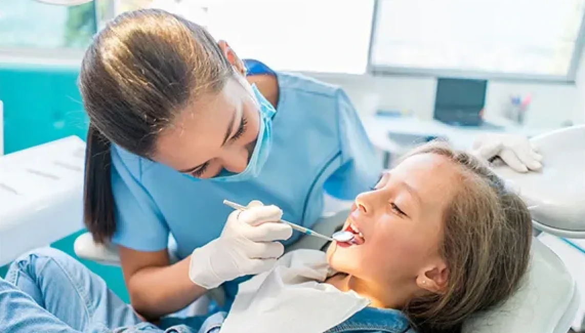 Dental hygienist examining a young girl’s teeth during a routine dental checkup.