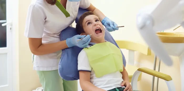 Young boy at a pediatric dental exam while the dentist checks his mouth and airway health, supporting early airway health and child development.