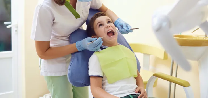 Young boy at a pediatric dental exam while the dentist checks his mouth and airway health, supporting early airway health and child development.