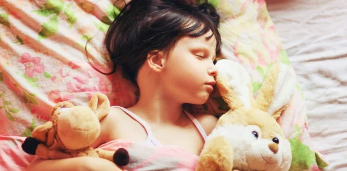 Airway Dentistry for Better Sleep at Atkins & Anderson DDS — child asleep in bed holding toys, resting comfortably.