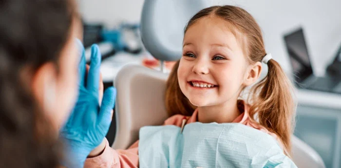 Child sitting in chair dentist chair smiling, dentist is giving the child a high five while wearing a glove, article title "Why Early Airway Screening (Ages 3-12) Matters for Lifelong Health"