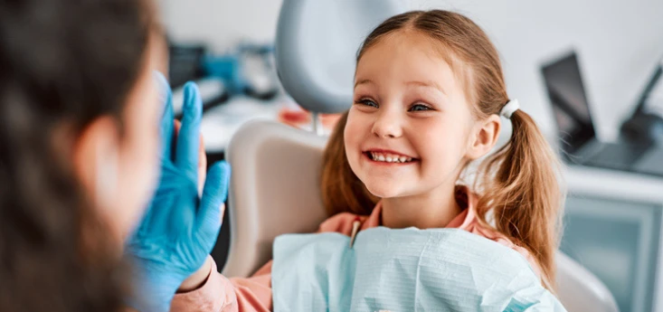 Child sitting in chair dentist chair smiling, dentist is giving the child a high five while wearing a glove, article title "Why Early Airway Screening (Ages 3-12) Matters for Lifelong Health"